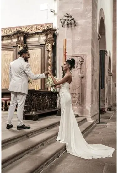 Die Braut und der Bräutigam interagieren liebevoll an den Stufen eines prunkvollen Altars in einer alten Kirche.