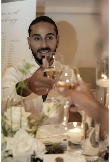 Der Bräutigam hebt ein Glas Champagner für einen Toast, umgeben von romantischer Tischdekoration mit Kerzen und Blumen.