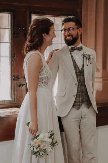Frisch verheiratetes Brautpaar bei der Hochzeit, Bräutigam im hellen Hochzeitsanzug mit Weste und Fliege