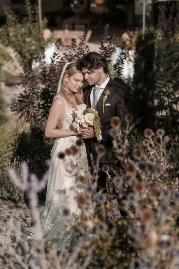 Brautpaar innig im Garten, Braut hält weißen Blumenstrauß