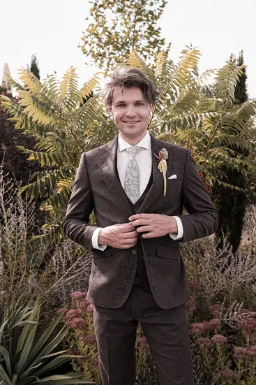 Bräutigam lächelt in die Kamera mit herbstlichem Hintergrund