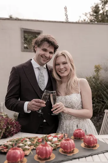 Brautpaar stößt mit Sekt an vor einer gedeckten Tafel