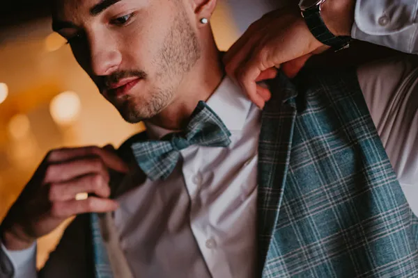 Bräutigam trägt eine stilvolle Weste als Teil seines Hochzeitsoutfits im Schlösschen