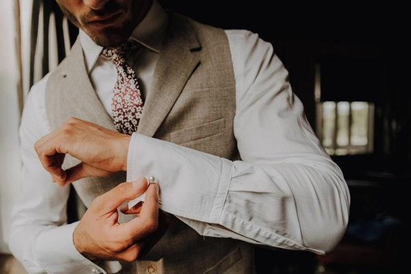 Nahaufnahme eines Bräutigams, der elegante Manschettenknöpfe an seinem Hochzeitsanzug befestigt